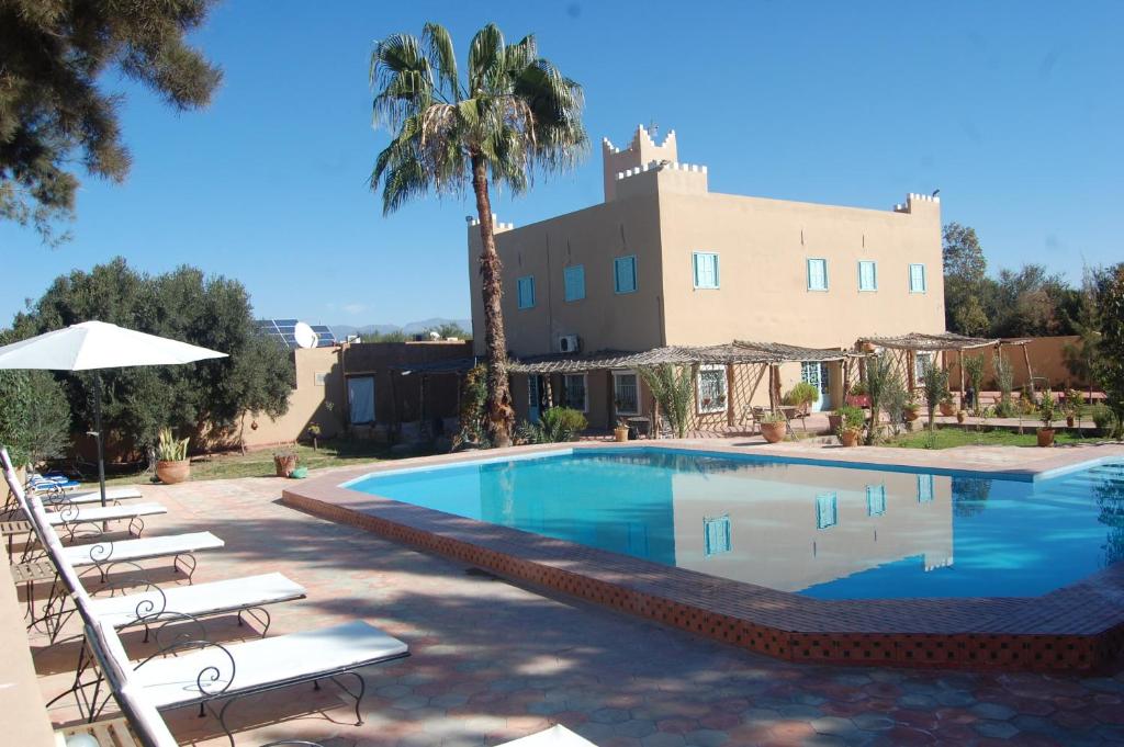 a swimming pool with chairs and a building in the background at Gite Souss in Oulad Teïma