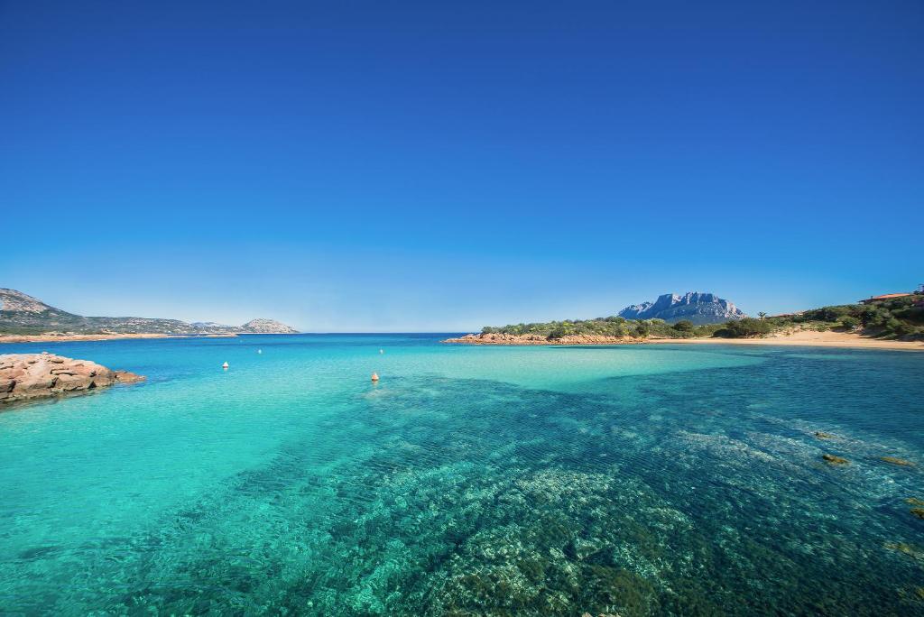 een uitzicht op een strand met blauw water bij Hotel Ollastu in Costa Corallina