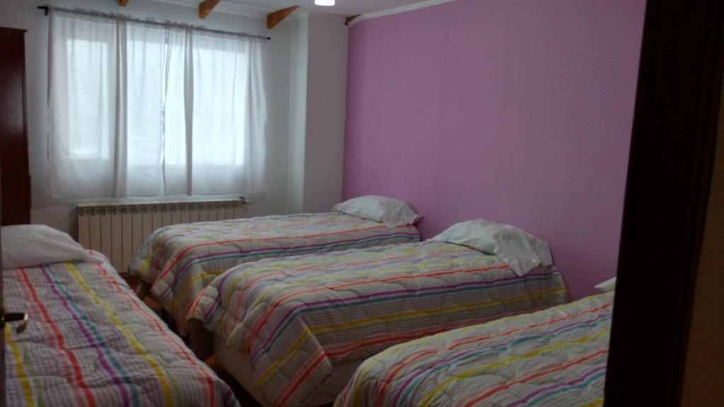 three beds in a room with purple walls and a window at Isla de Lagos II in Ushuaia