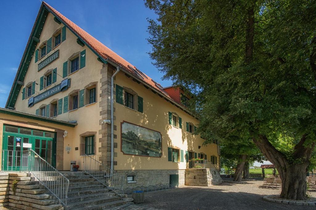 ein Gebäude mit einer Treppe vor einem Baum in der Unterkunft Gastwirtschaft & Hotel Hallescher Anger in Naumburg