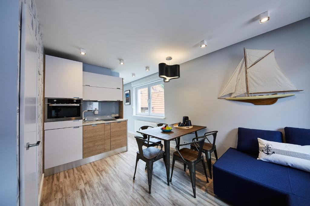 a small kitchen with a table and a blue couch at Victus Apartamenty, Apartamenty Delux in Sopot