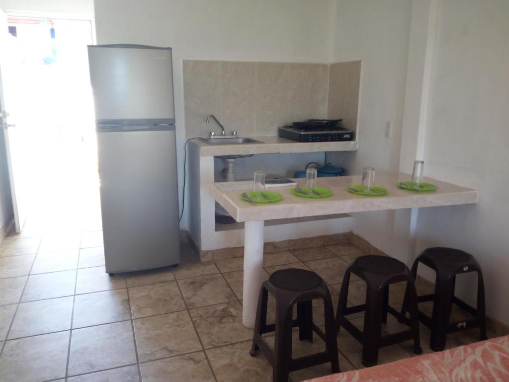 a kitchen with a table with stools and a refrigerator at Posada El Balcon in Rincon de Guayabitos