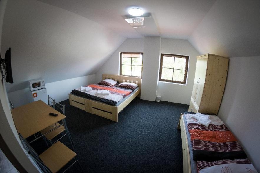 a room with two beds and a desk and two windows at Penzion Podyjí in Znojmo