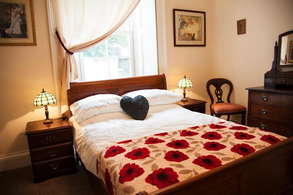a bedroom with a bed with red flowers on it at Clara Lodge Guesthouse in Dunfermline