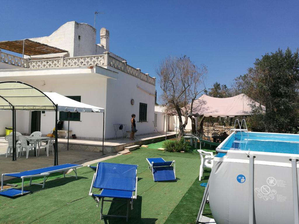 a backyard with a pool and chairs and a house at Casa Vacanze Cisternella in Torre San Giovanni Ugento