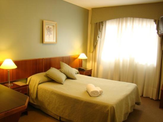 a hotel room with a bed with two towels on it at Hotel Costa Limay in Plottier