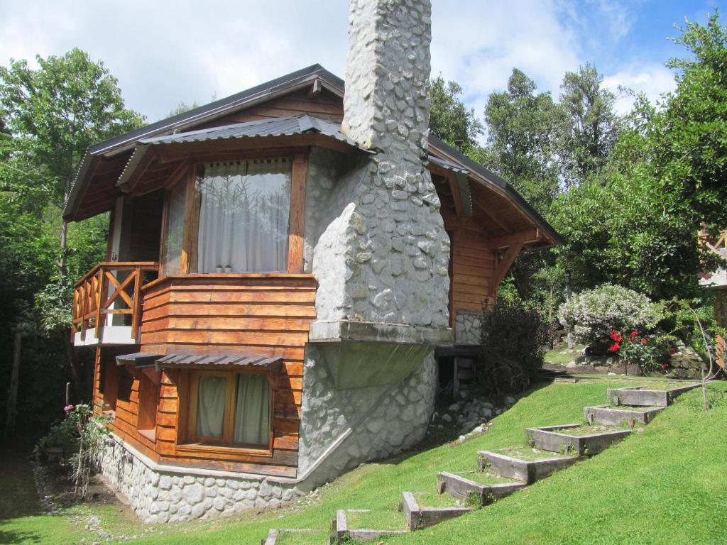 Cabaña de madera con chimenea de piedra y algunas escaleras en Villa Ålborg en Villa La Angostura