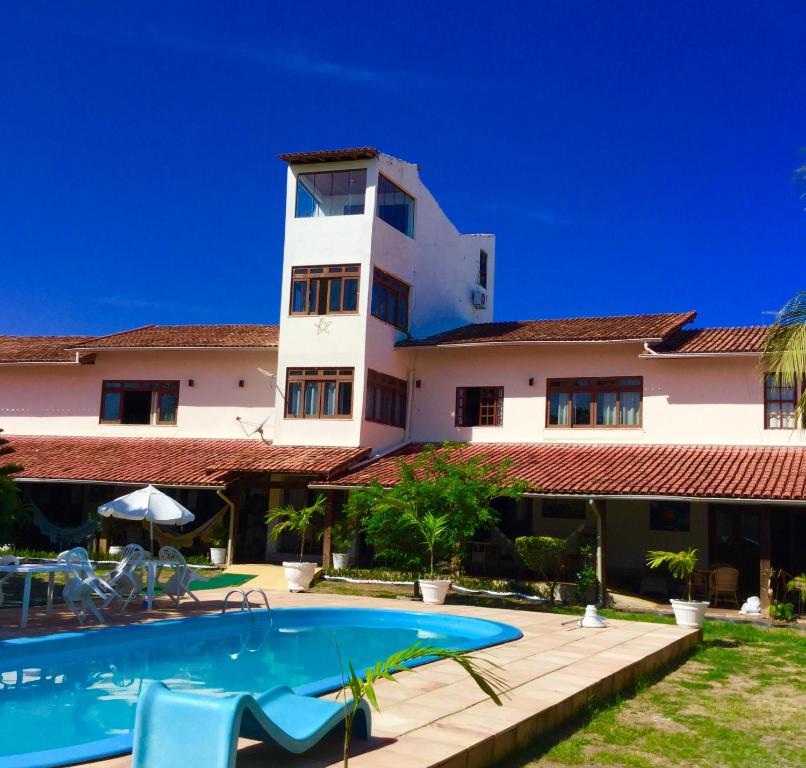 een resort met een zwembad en een gebouw bij Pousada da Mércia - Itapuã (BA) in Salvador