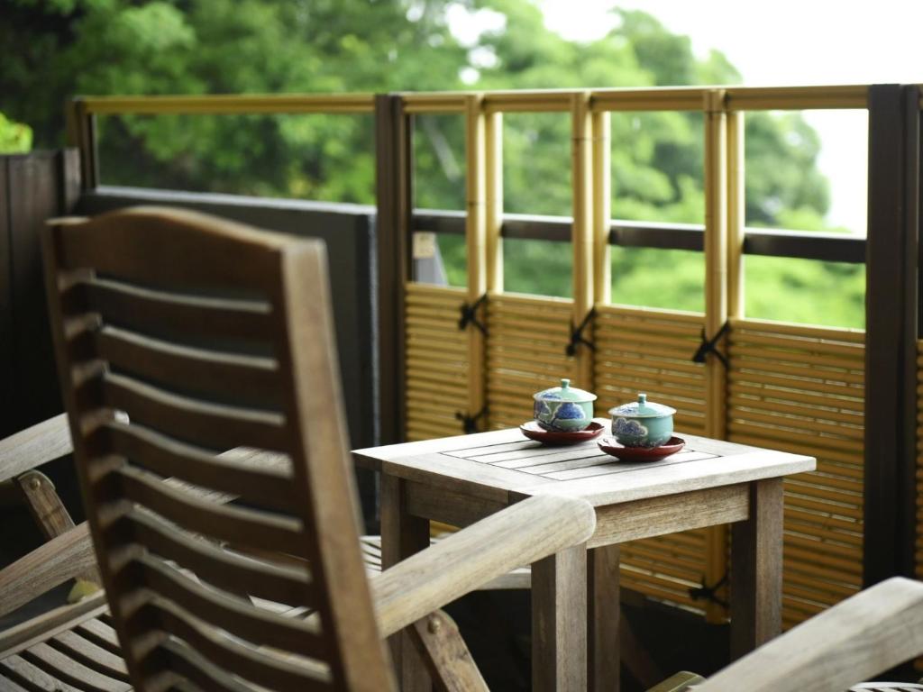 a wooden table with two cups on it on a balcony at Shin Kaikatei Izumi in Izu