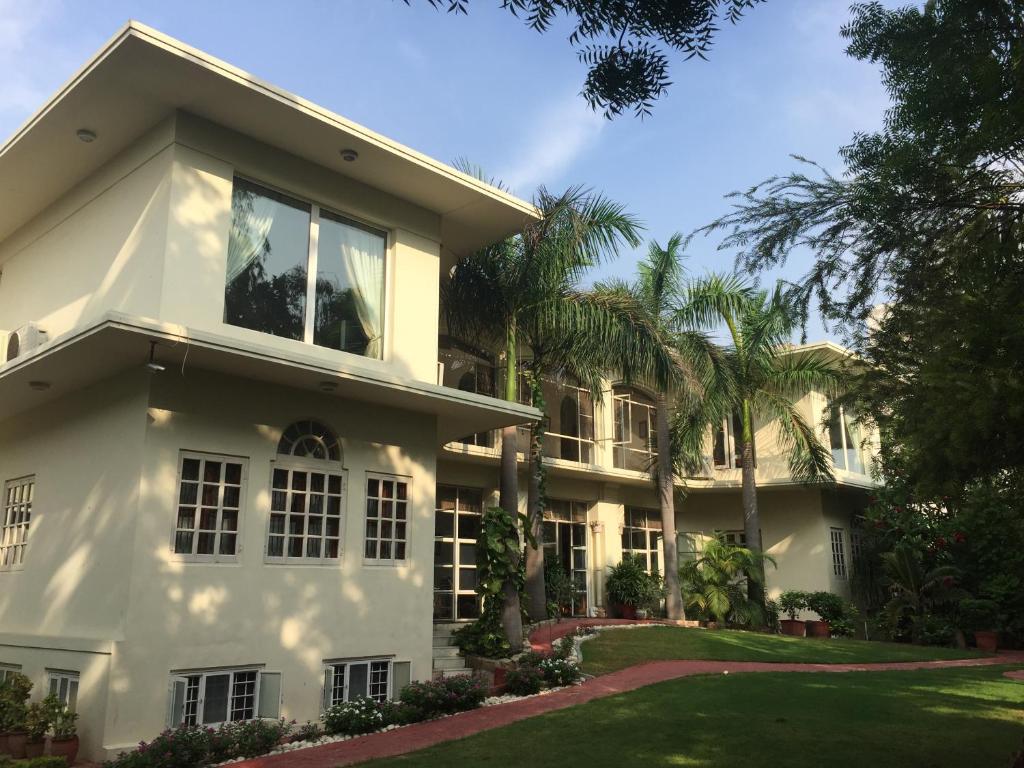 a white house with palm trees in front of it at Barwara Kothi in Jaipur