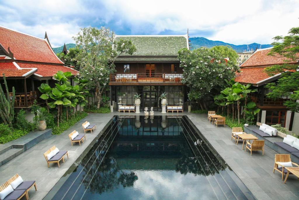 a swimming pool in front of a building with a house at Villa Mahabhirom - SHA Plus in Chiang Mai