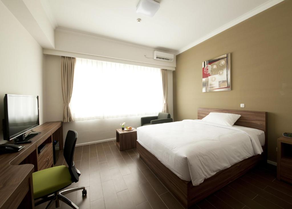 a hotel room with a bed and a television at Sancrest Residence Deltamas in Cikarang