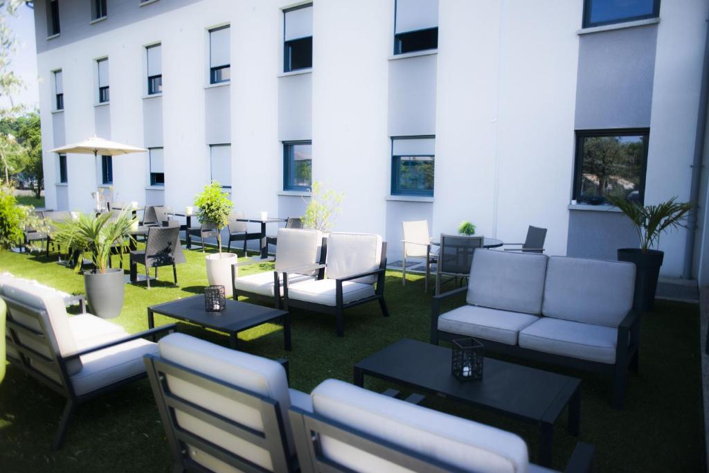 un patio avec des chaises et des tables en face d'un bâtiment dans l'établissement All Suites Besançon, à Besançon