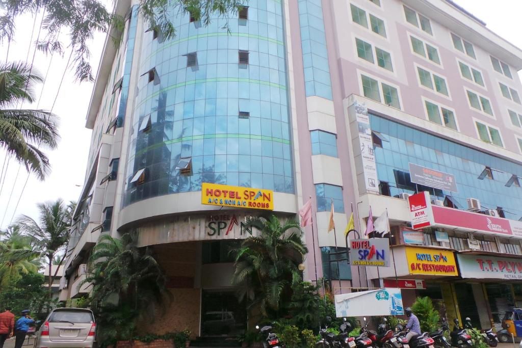 een hoog gebouw in een stadsstraat met palmbomen bij Hotel Span in Kozhikode