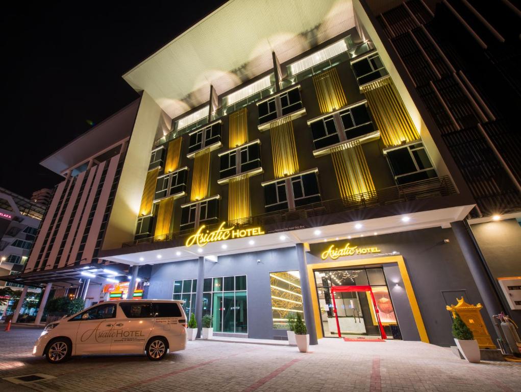 un coche aparcado delante de un edificio por la noche en Asiatic Hotel en Melaka