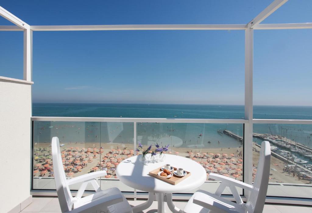 a white table and chairs on a balcony with a beach at Residence Terminus in Rimini