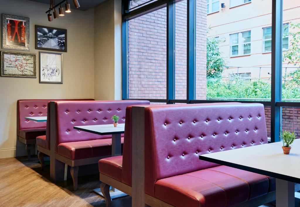 a restaurant with purple chairs and tables and windows at Leonardo Hotel Manchester Central in Manchester