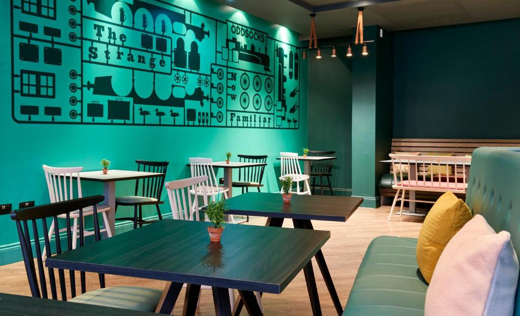 a restaurant with tables and chairs and a green wall at Leonardo Hotel Manchester Central in Manchester