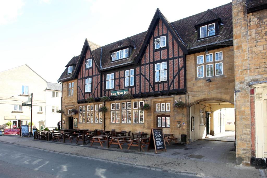 a building with tables and chairs in front of it at Half Moon, Sherborne by Marston's Inns in Sherborne