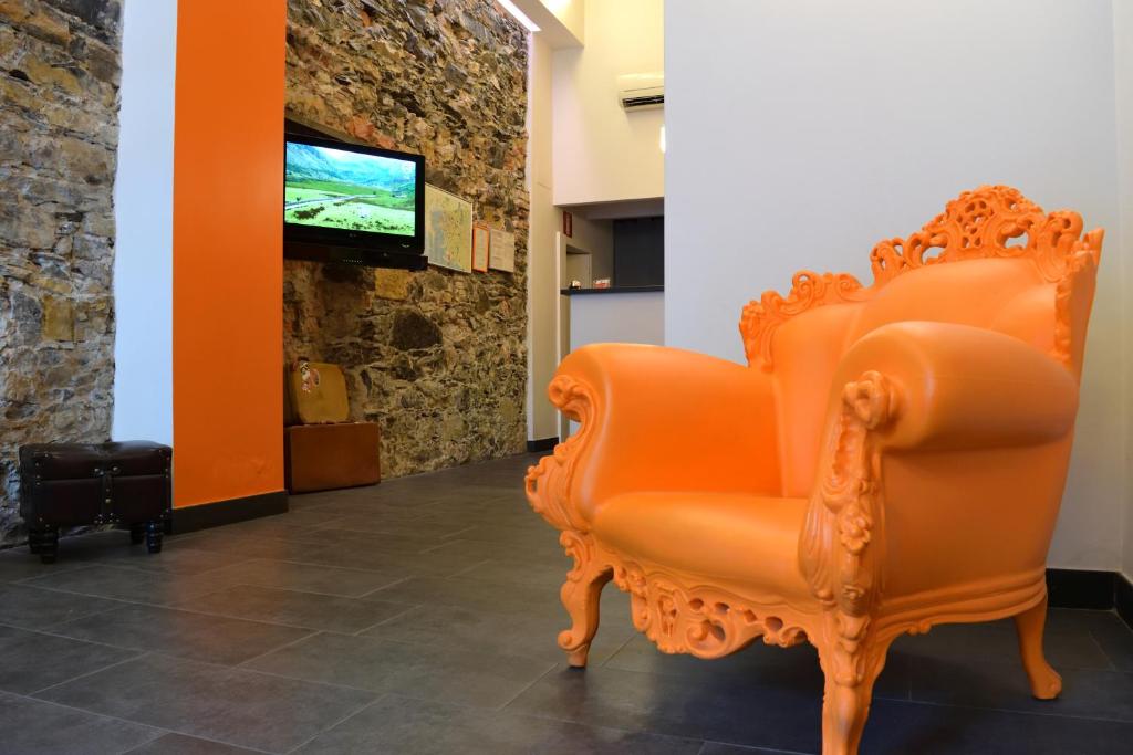 una sedia arancione seduta in un corridoio con TV di Hotel Fiume a Genova
