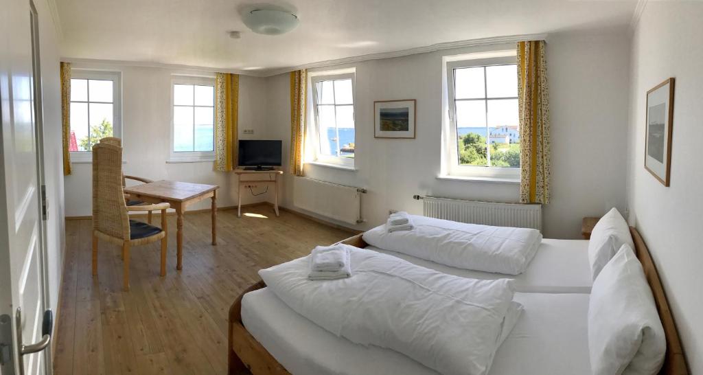 a bedroom with two beds and a desk and a table at Pension "Strandhotel" in Vitte