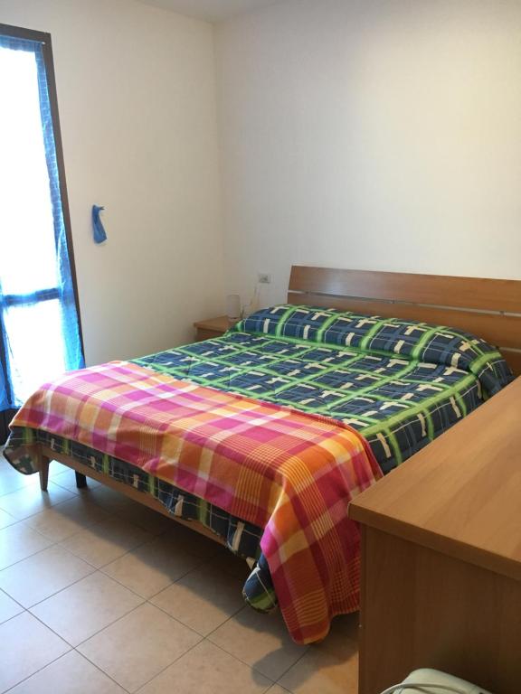 Un dormitorio con una cama con una manta de colores. en Apartment in Residence King's Bay en Fano