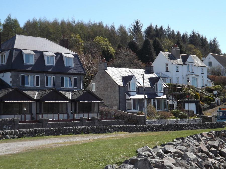 um grupo de casas numa colina com árvores em The Mariner Hotel em Kippford