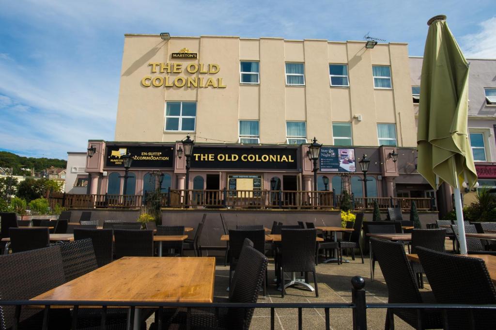 um restaurante com mesas e cadeiras em frente a um edifício em Old Colonial, Weston-Super-Mare by Marston's Inns em Weston-super-Mare