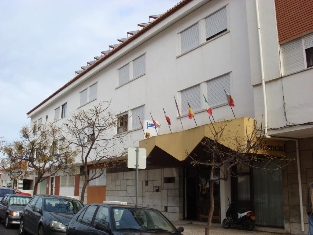 um edifício branco com bandeiras na frente em Residencial Habimar em Sines