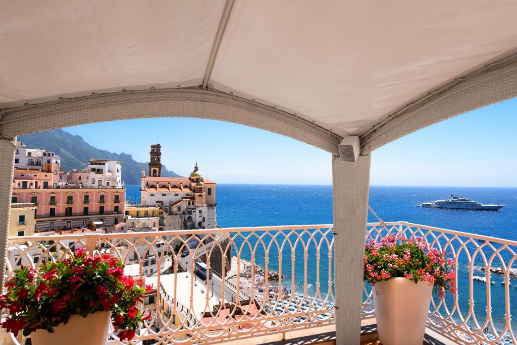 a balcony overlooking the ocean with a boat in the distance at Palazzo Ferraioli - Hotel & Wellness in Atrani