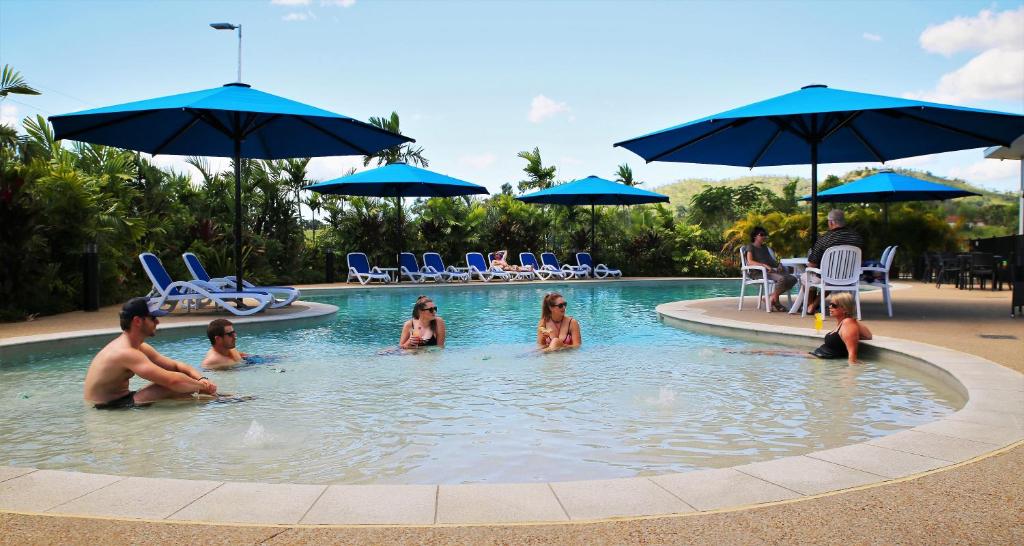people sitting in a pool with umbrellas at Korte's Resort in Rockhampton