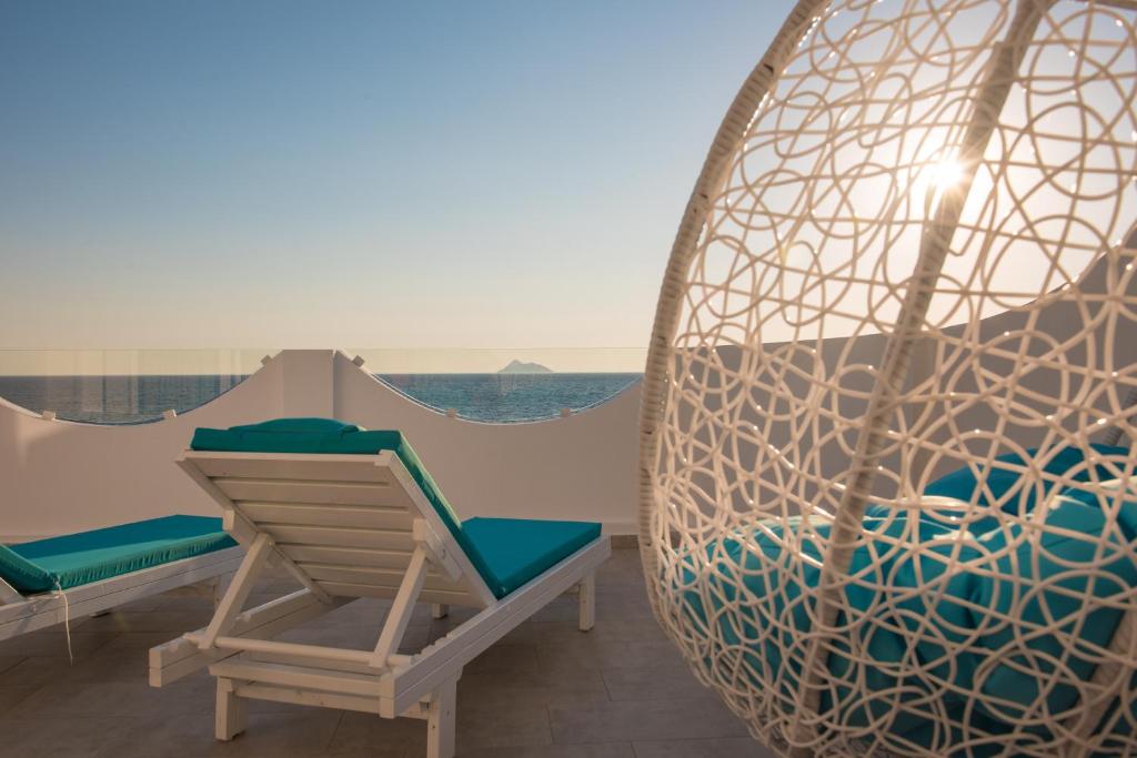 een veranda met een schommel en een stoel en de oceaan bij Aristodimos Luxury Apartments in Kalamaki