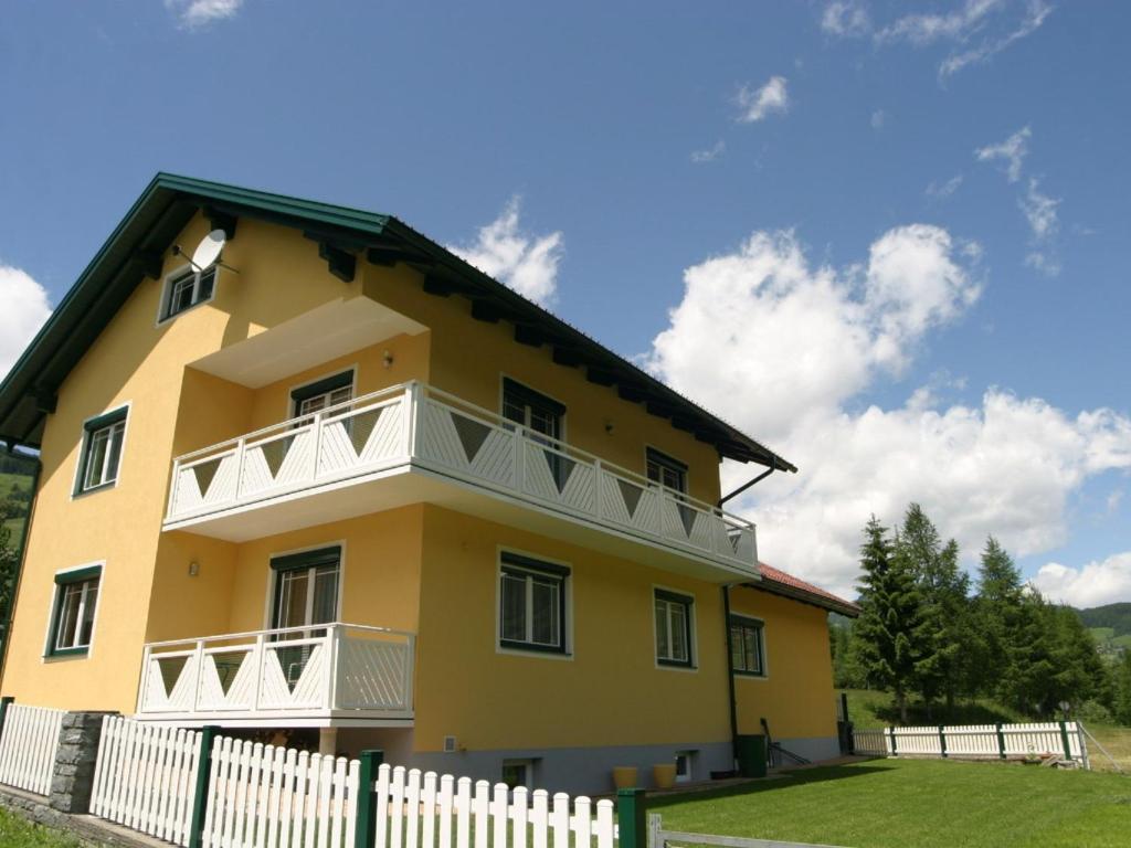 een geel huis met witte balkons en een hek bij Apartment in Rennweg am Katschberg near ski area in Rennweg