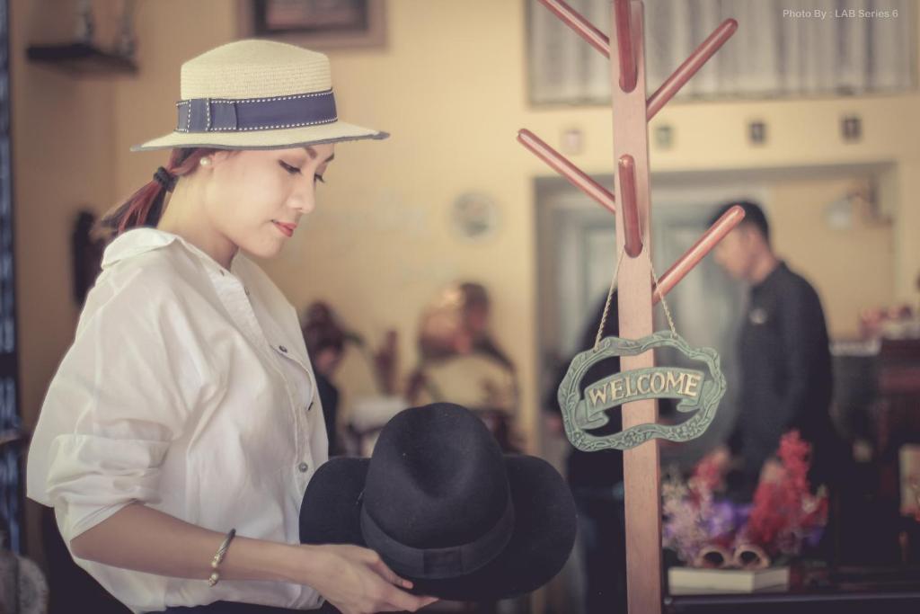a woman is holding a hat on a display at The Unforgotten B&B in Bangkok