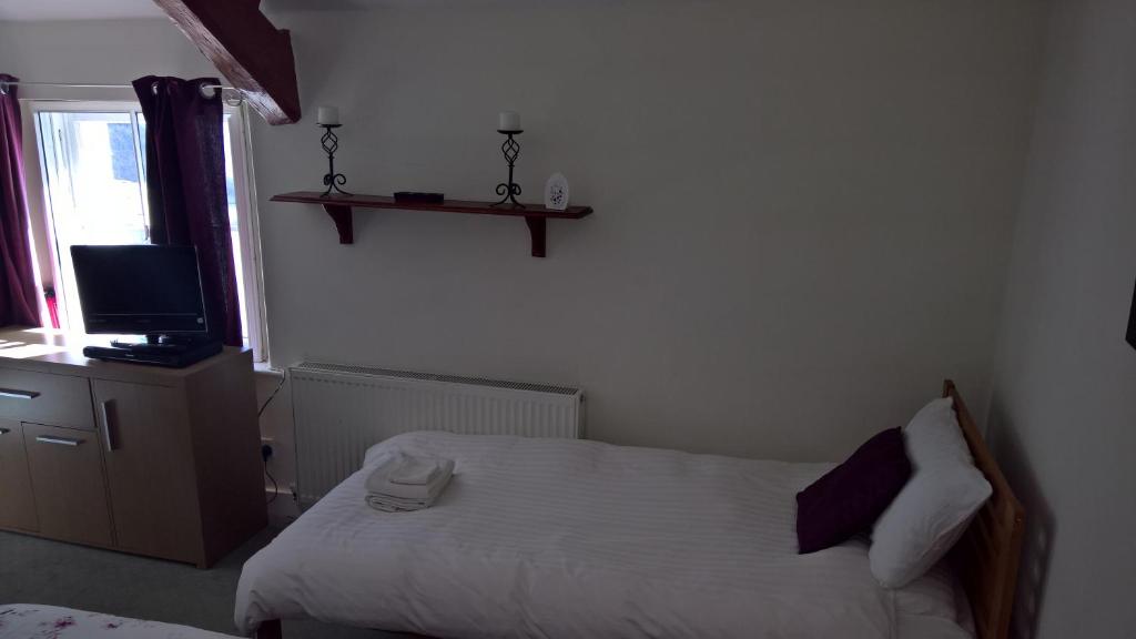 a small bedroom with a bed and a television at Black Bull Hotel in Lancaster