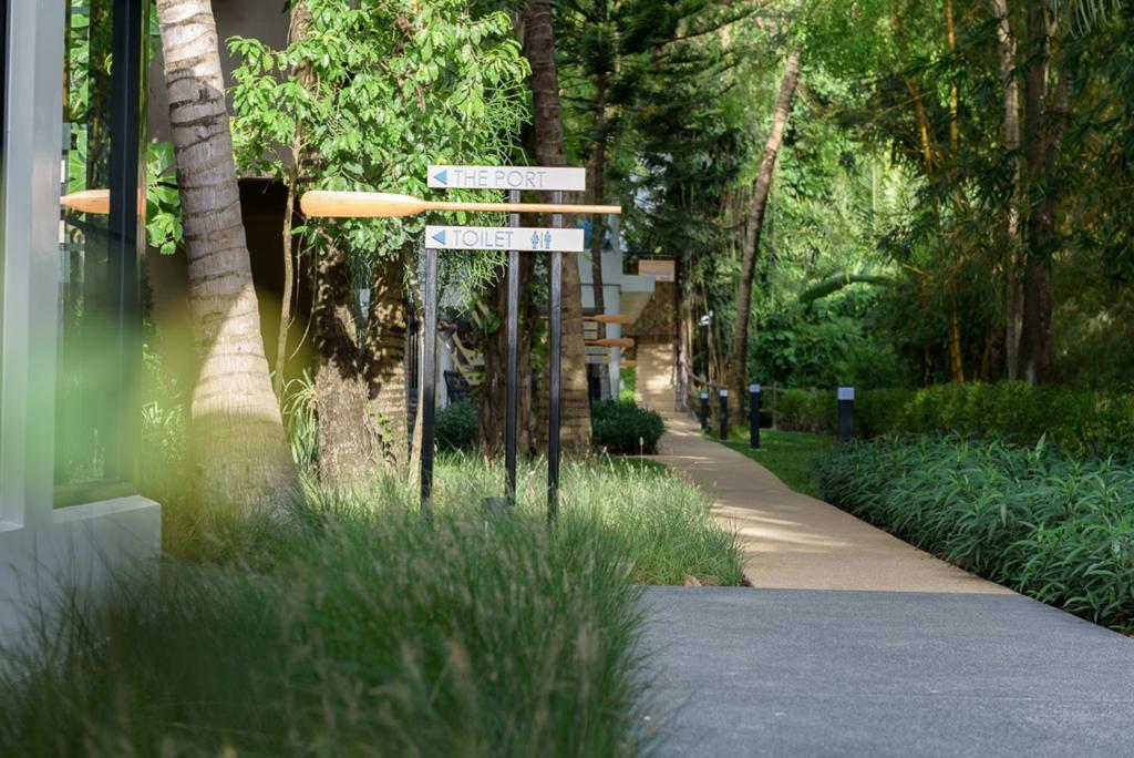 a street sign in the grass next to a sidewalk at Deevana Krabi Resort in Ao Nang Beach