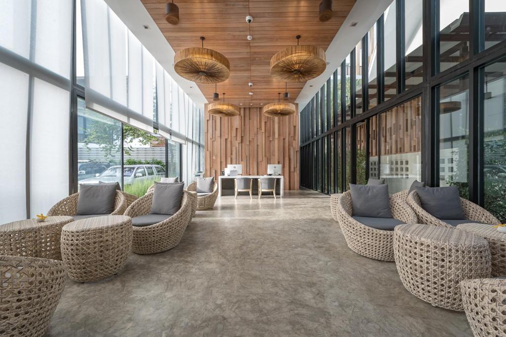 a lobby with wicker chairs and tables in a building at Deevana Krabi Resort in Ao Nang Beach