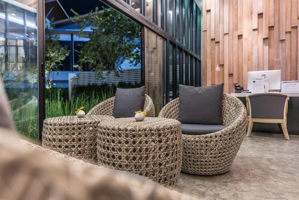 two wicker chairs and chairs with pillows on a patio at Deevana Krabi Resort in Ao Nang Beach