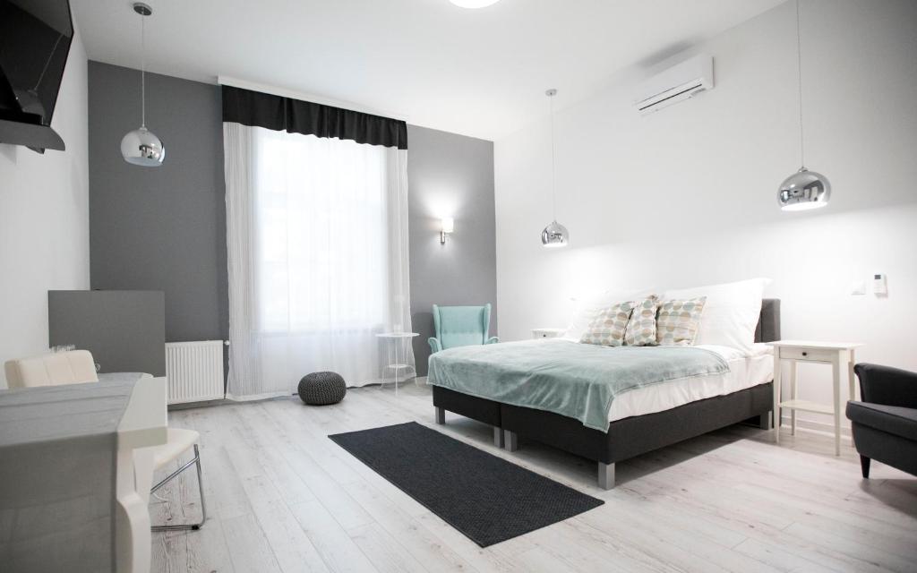 a white bedroom with a bed and a window at City Center Stúdió Apartmanok in Szeged
