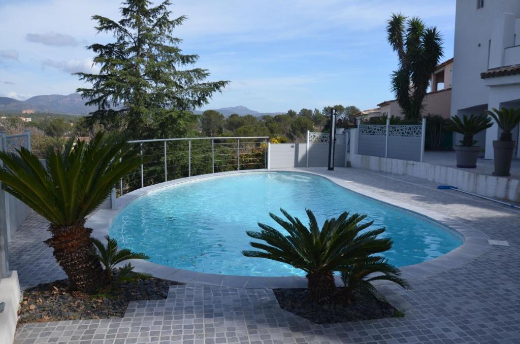 a swimming pool with two palm trees next to a building at Belle maison avec piscine dans les hauteurs à Saint Raphael in Saint-Raphaël