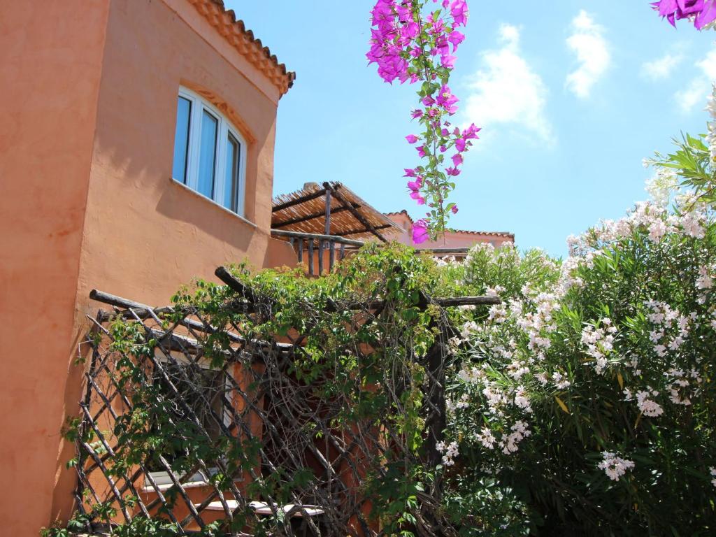 イーゾラ・ロッサにあるBelvilla by OYO Holiday Home in Sardinia Italyの柵と花の前の建物