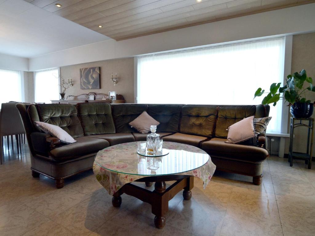 a living room with a leather couch and a coffee table at Spacious holiday home in Ruiselede with a garden in Ruiselede