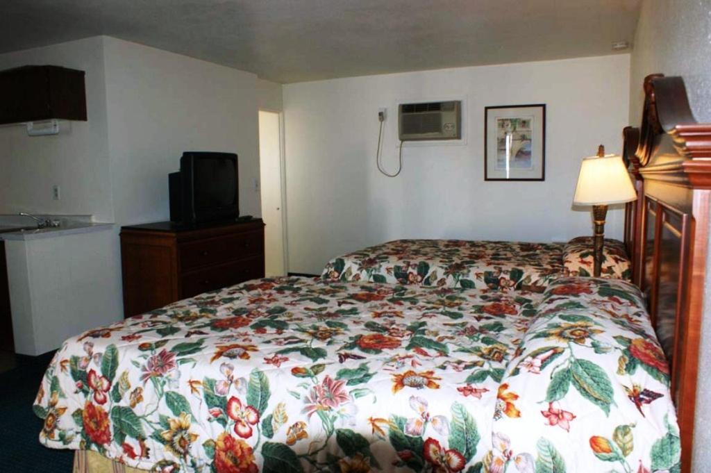 a bedroom with a bed with a flowered comforter at HWY Express Inn and Suites in Thatcher