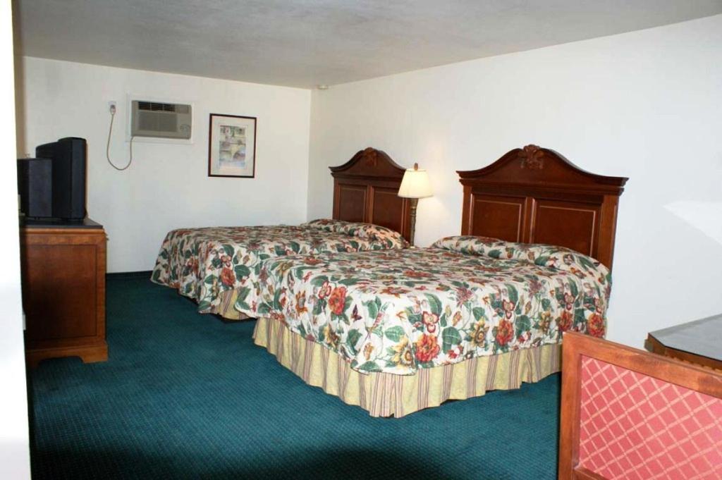 a hotel room with two beds and a television at HWY Express Inn and Suites in Thatcher