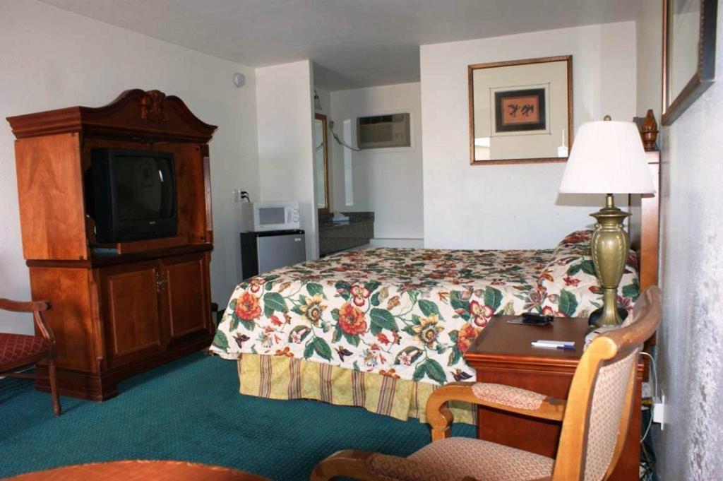 a hotel room with a bed and a desk and a tv at HWY Express Inn and Suites in Thatcher