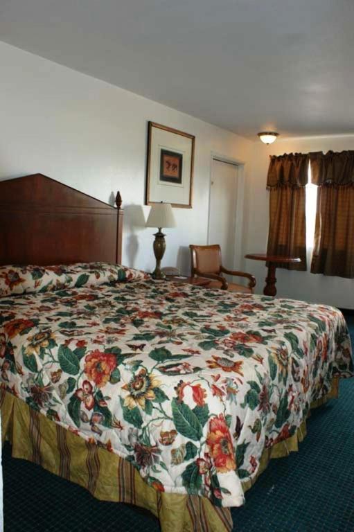 a bedroom with a bed with a floral bedspread at HWY Express Inn and Suites in Thatcher