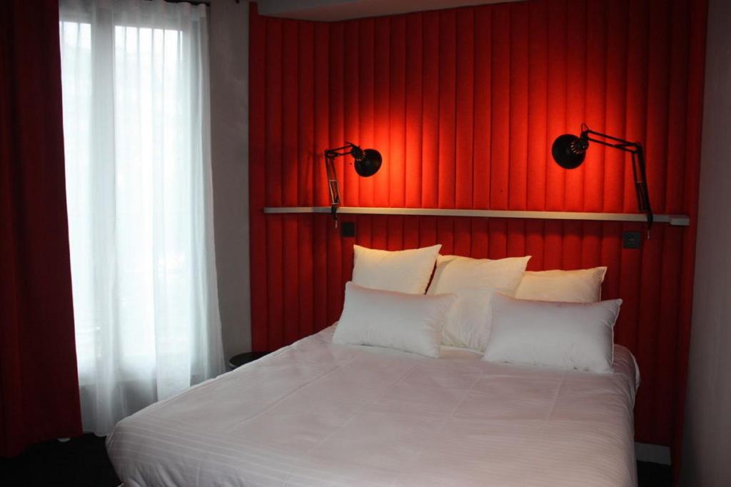 1 dormitorio con cama blanca y pared roja en Hôtel Saint Marcel, en París