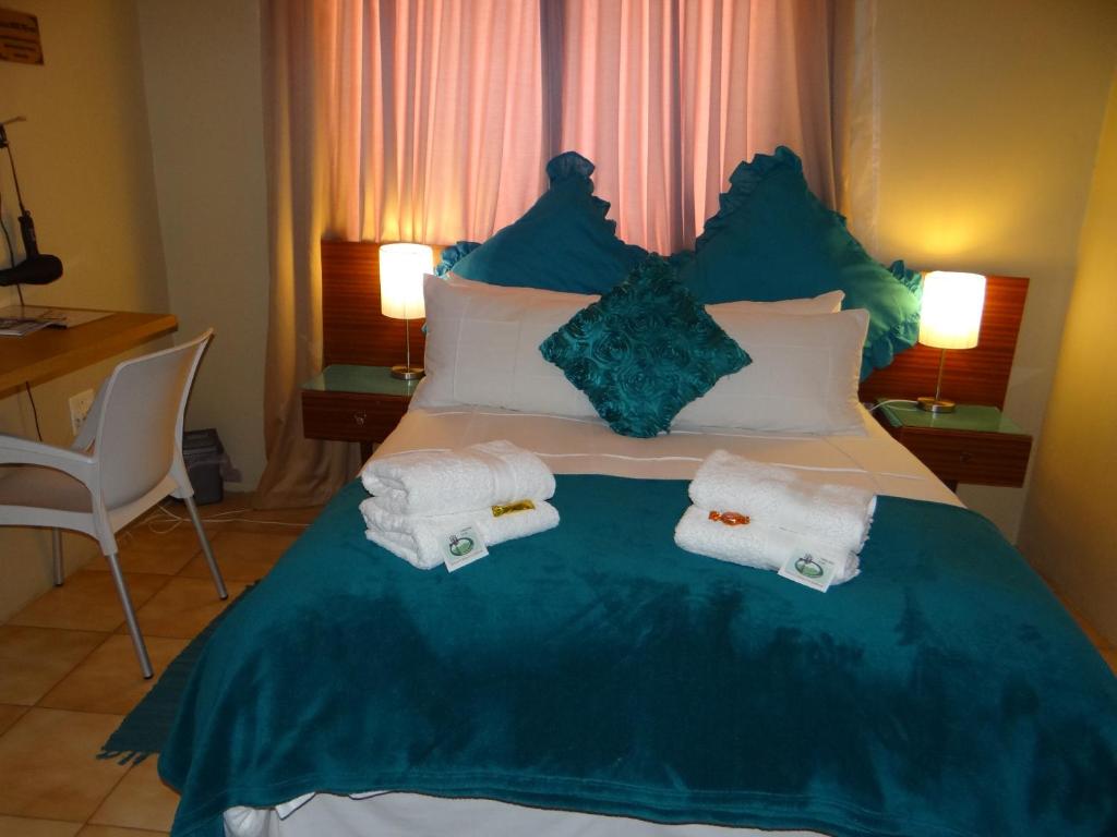 1 dormitorio con 1 cama con toallas en Obrigado Guest House, en De Aar