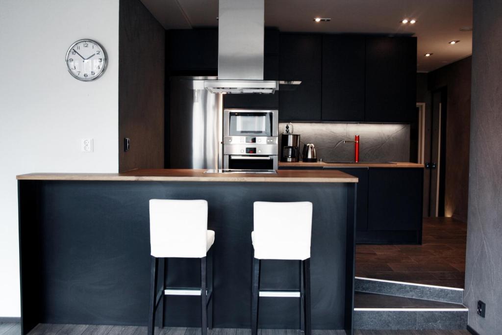 a kitchen with black cabinets and white bar stools at Apartment in Jakobstad / Pietarsaari in Pietarsaari