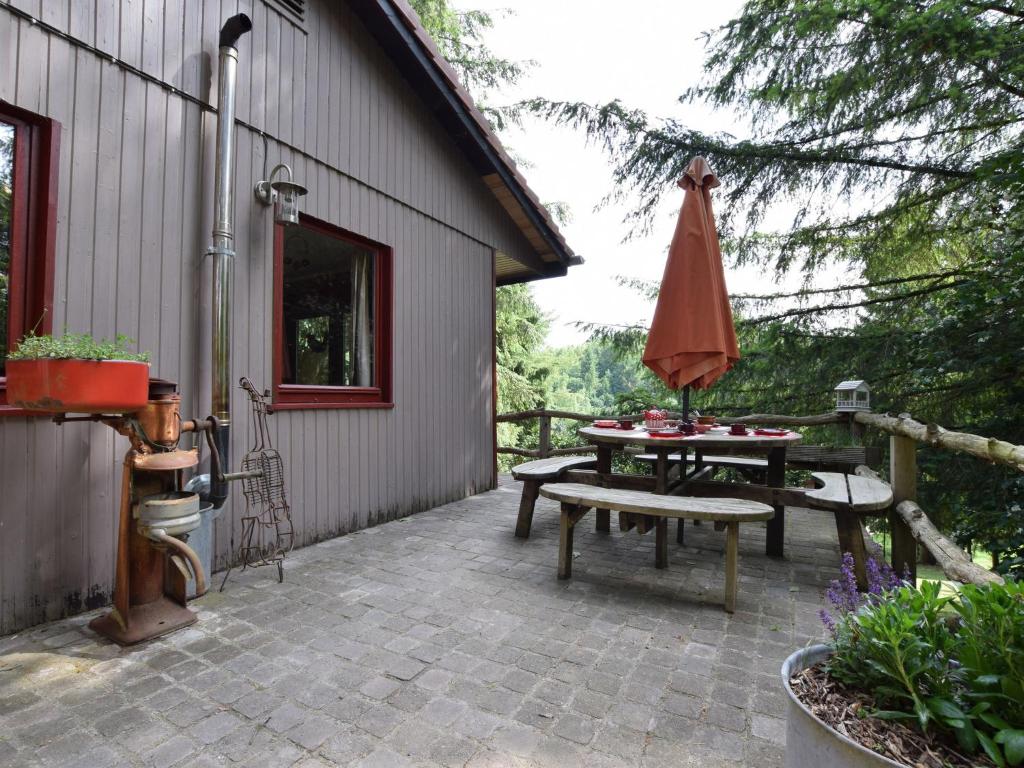 une terrasse avec une table et un parasol dans l'établissement Chalet in a green and peaceful environment, à Houffalize